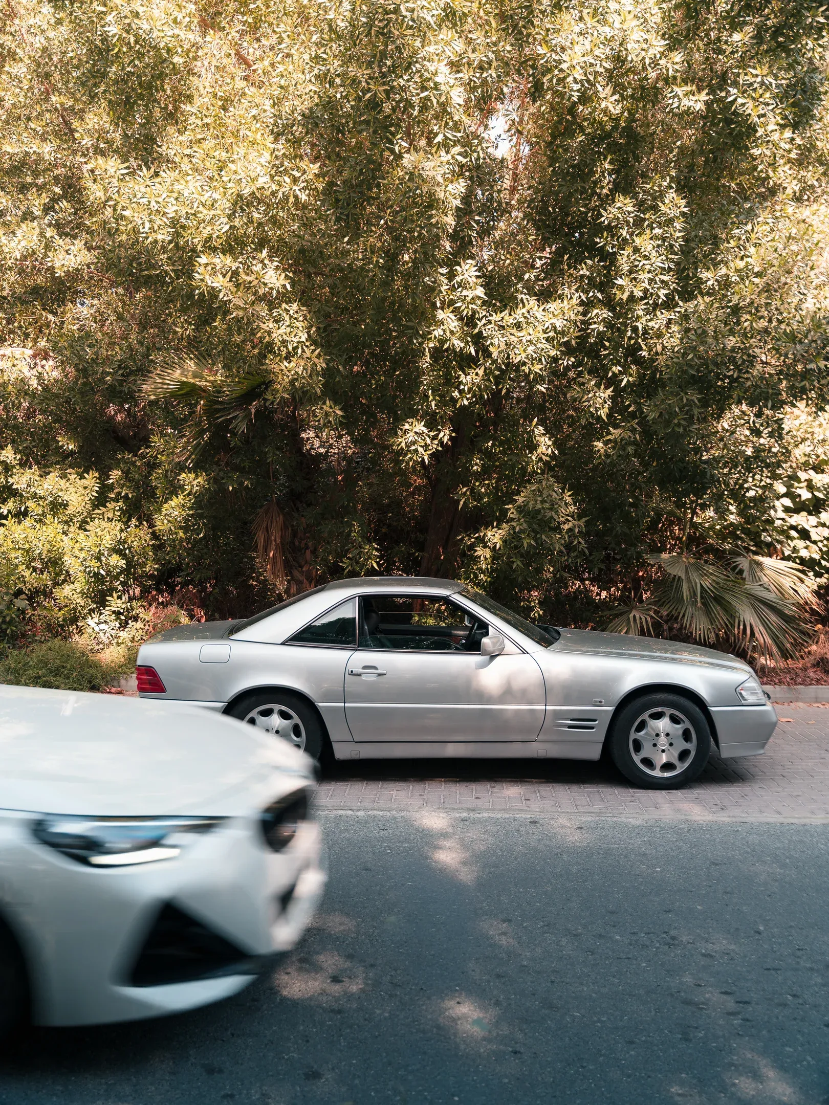 Generations apart: The timeless silhouette of the R129 SL 500 contrasted against the blur of modern Dubai traffic.