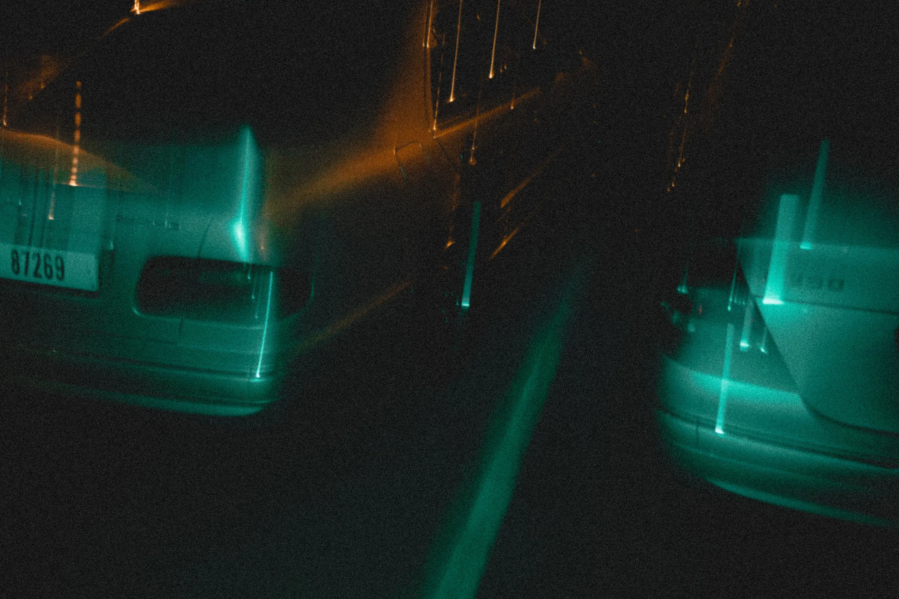 Artistic blur of a silver car at night, teal and orange highlights.